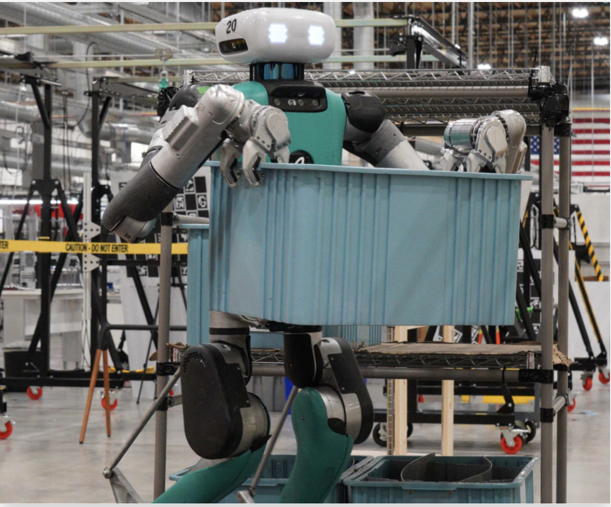 Humanoid robot carrying bin in warehouse